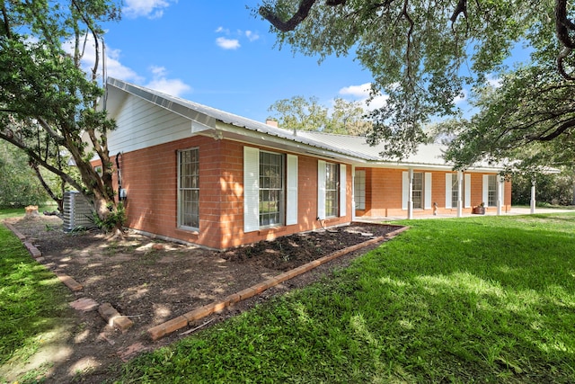 115 Old Caney Rd, Wharton, TX 77488 - view of front of house featuring central AC, brick siding, a front lawn, and metal roof