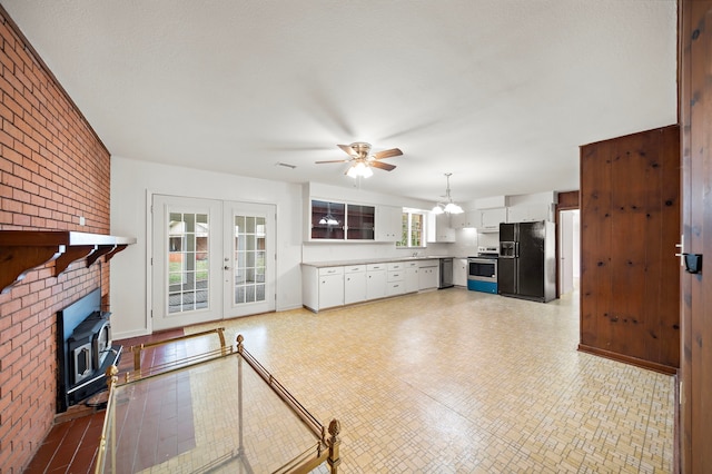 115 Old Caney Rd, Wharton, TX 77488 - unfurnished living room with ceiling fan, a wood stove, french doors, and brick wall