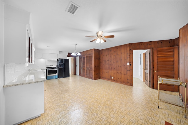 115 Old Caney Rd, Wharton, TX 77488 - kitchen with range, black fridge, a ceiling fan, wooden walls, and white cabinets