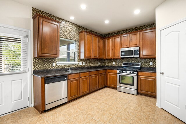 506 Stream Mill Ln, Katy, TX 77494 - kitchen with stainless steel appliances, dark countertops, a sink, tasteful backsplash, and recessed lighting