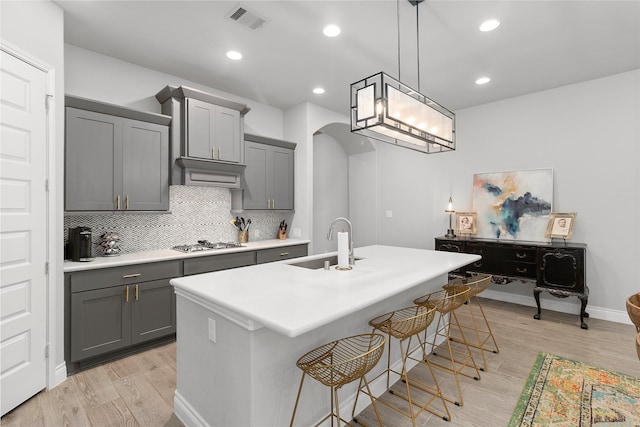 kitchen with a sink, gray cabinetry, stainless steel gas stovetop, light wood-type flooring, and recessed lighting