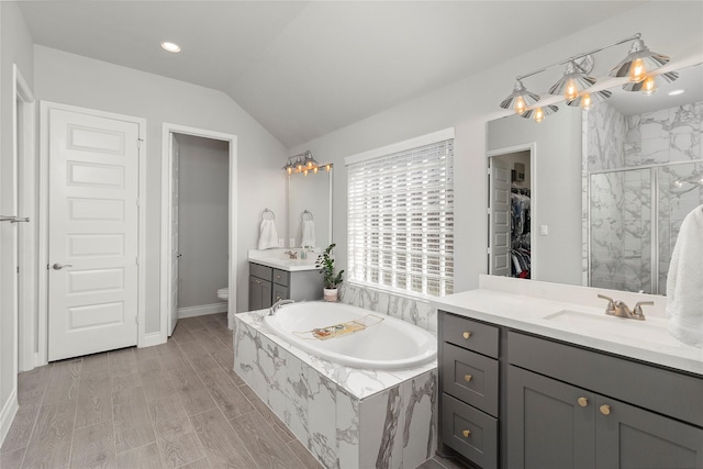bathroom with a stall shower, lofted ceiling, vanity, toilet, and a garden tub