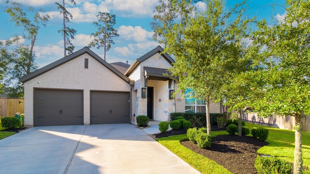 view of front of home with a garage, concrete driveway, fence, and stone siding