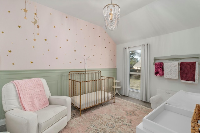 bedroom with wainscoting, vaulted ceiling, a chandelier, light wood finished floors, and wallpapered walls