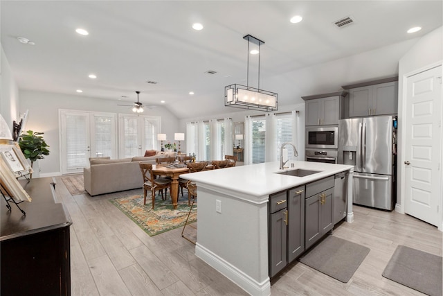kitchen with stainless steel appliances, a sink, gray cabinetry, lofted ceiling, and light countertops
