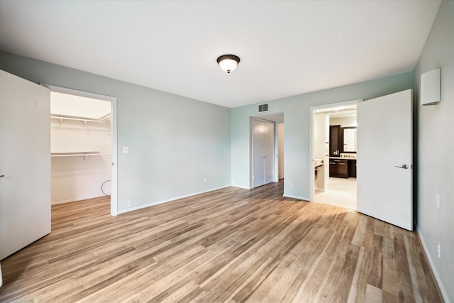 6549 Bayou Glen Rd, Houston, TX 77057 - unfurnished bedroom with light wood-style flooring, a spacious closet, a closet, baseboards, and ensuite bathroom