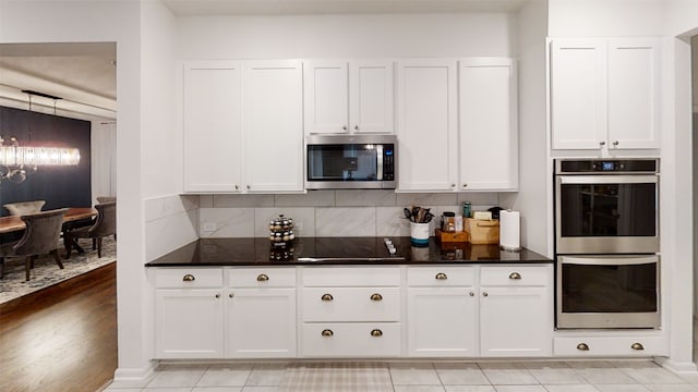 kitchen featuring appliances with stainless steel finishes, a chandelier, white cabinetry, and tasteful backsplash