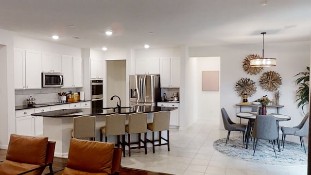 kitchen featuring stainless steel appliances, dark countertops, a sink, decorative backsplash, and recessed lighting