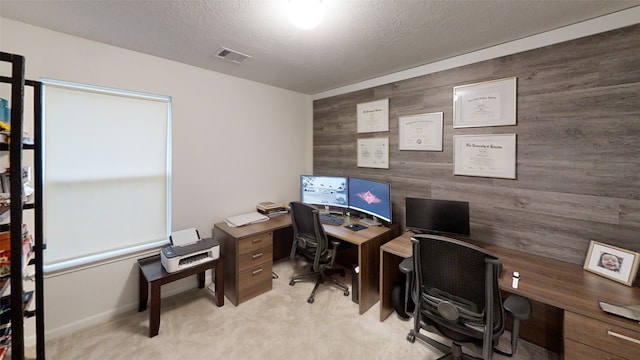 office with light colored carpet, an accent wall, wooden walls, and a textured ceiling