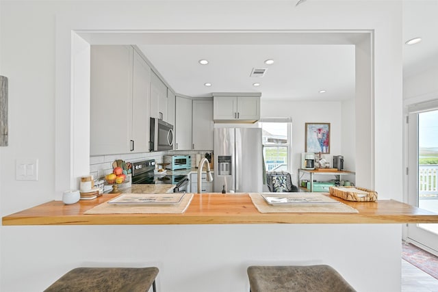 16716 Tahiti Way, Galveston, TX 77554 - kitchen featuring stainless steel appliances, a peninsula, healthy amount of natural light, backsplash, and recessed lighting