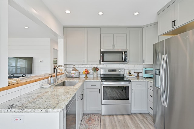 16716 Tahiti Way, Galveston, TX 77554 - kitchen featuring appliances with stainless steel finishes, a sink, a peninsula, decorative backsplash, and recessed lighting
