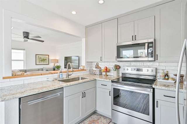 16716 Tahiti Way, Galveston, TX 77554 - kitchen featuring stainless steel appliances, a sink, a ceiling fan, light stone countertops, and backsplash