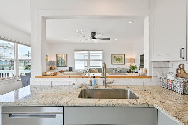 16716 Tahiti Way, Galveston, TX 77554 - kitchen with dishwasher, a sink, a ceiling fan, light stone counters, and tasteful backsplash