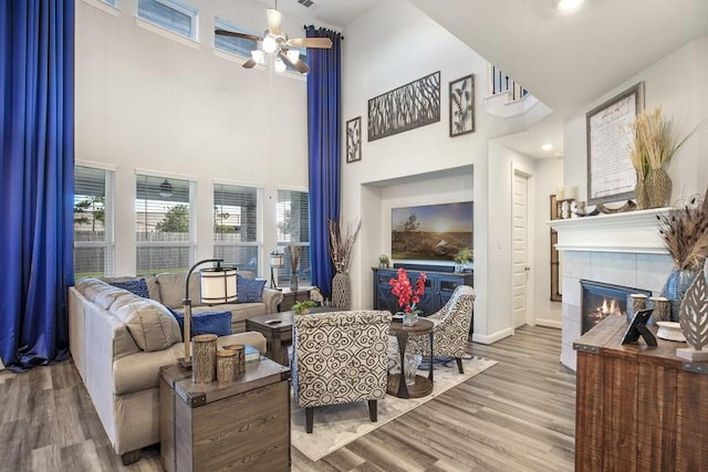 13814 Russell Ct, Mont Belvieu, TX 77523 - living room with a high ceiling, a tile fireplace, ceiling fan, wood finished floors, and baseboards