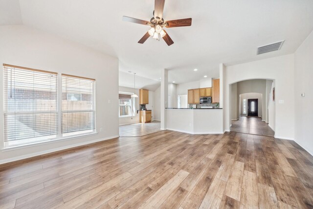 4226 Texian Forest Trl, Humble, TX 77346 - unfurnished living room with arched walkways, a ceiling fan, light wood finished floors, baseboards, and vaulted ceiling