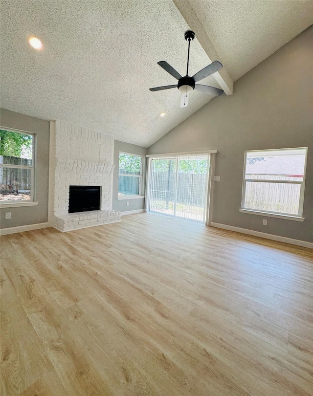 unfurnished living room featuring ceiling fan, wood finished floors, baseboards, beam ceiling, and a textured ceiling
