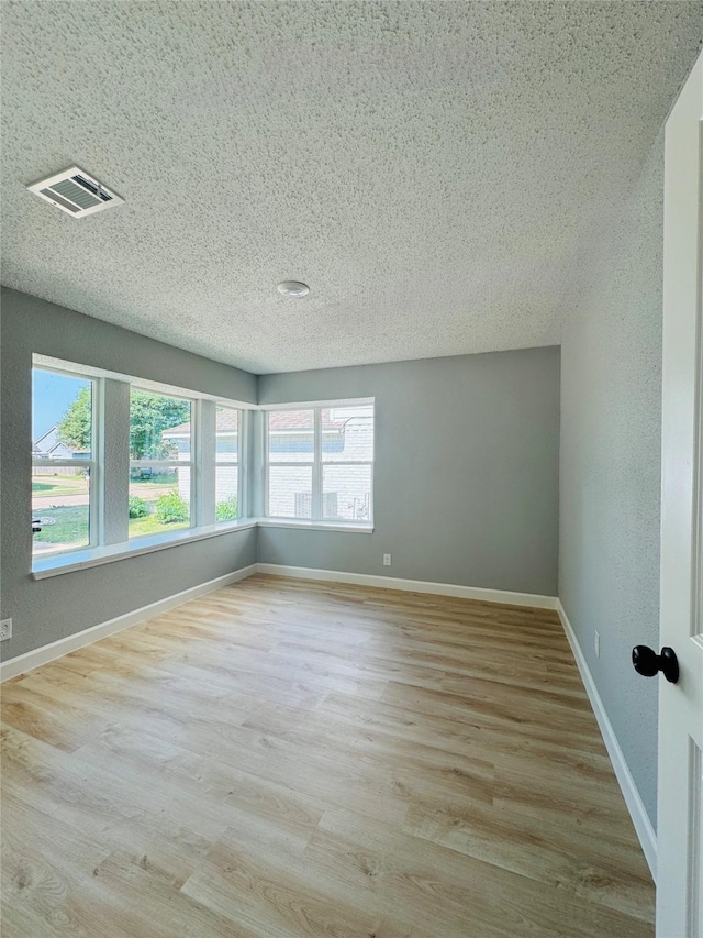 unfurnished room featuring wood finished floors, baseboards, and a textured ceiling