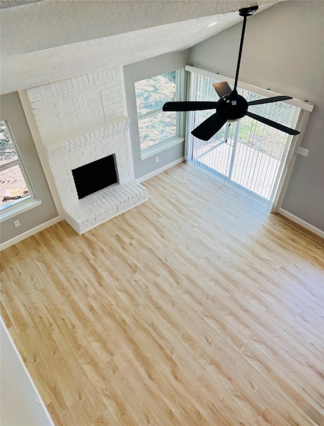 unfurnished living room with baseboards, wood finished floors, a textured ceiling, and lofted ceiling