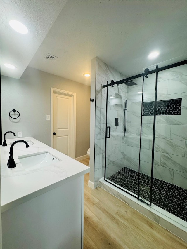 bathroom featuring wood finished floors, a shower stall, baseboards, recessed lighting, and toilet