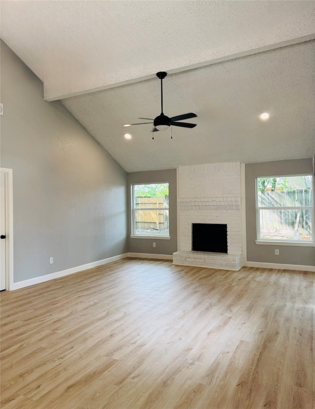 unfurnished living room featuring a ceiling fan, light wood finished floors, baseboards, a textured ceiling, and lofted ceiling