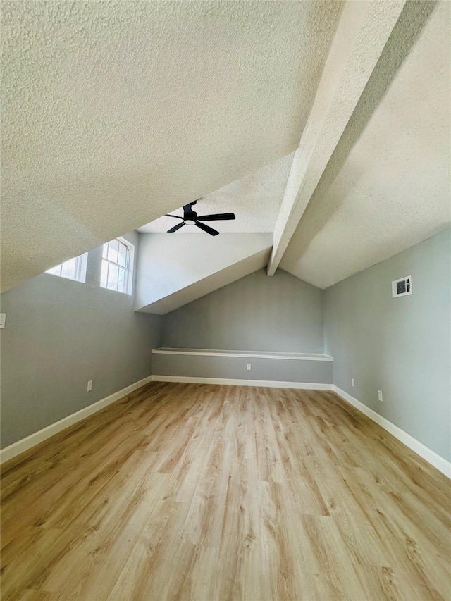 additional living space with a textured ceiling, wood finished floors, ceiling fan, and baseboards