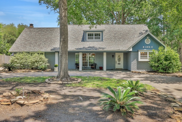 105 N Delmont Dr E, Conroe, TX 77301 - view of front facade featuring roof with shingles, brick siding, fence, a chimney, and covered porch