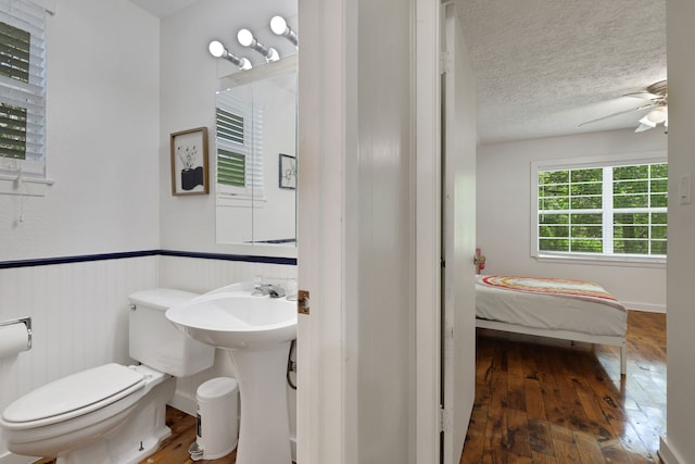 105 N Delmont Dr E, Conroe, TX 77301 - bathroom featuring wood-type flooring, toilet, ceiling fan, a wainscoted wall, and a textured ceiling