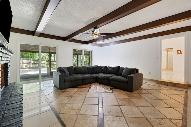 105 N Delmont Dr E, Conroe, TX 77301 - living room featuring a textured ceiling, beamed ceiling, a fireplace, a ceiling fan, and stone tile flooring