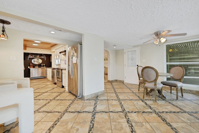 105 N Delmont Dr E, Conroe, TX 77301 - kitchen with stainless steel refrigerator with ice dispenser, arched walkways, inlaid floor details, a ceiling fan, and a textured ceiling