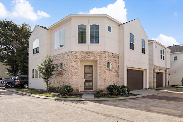 townhome / multi-family property with a garage, concrete driveway, and stucco siding