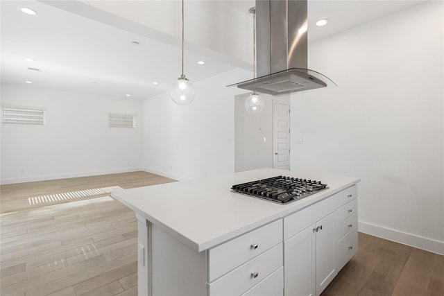 kitchen featuring island range hood, stainless steel gas cooktop, light wood finished floors, white cabinets, and baseboards