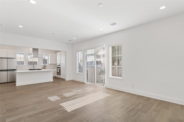 unfurnished living room with light wood-style flooring, baseboards, and recessed lighting