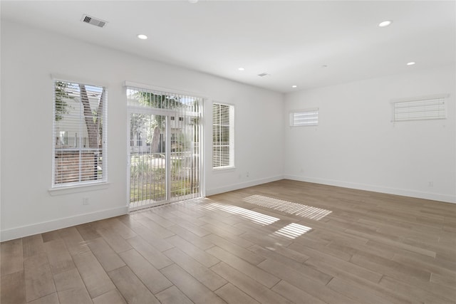 unfurnished room with healthy amount of natural light, light wood finished floors, baseboards, and recessed lighting