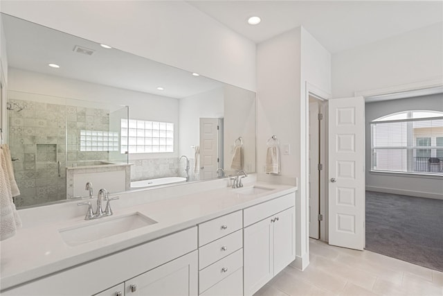 bathroom with healthy amount of natural light, a shower stall, tile patterned floors, recessed lighting, and double vanity