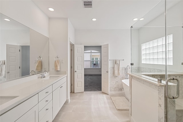bathroom with recessed lighting, tile patterned flooring, a freestanding tub, double vanity, and a shower stall