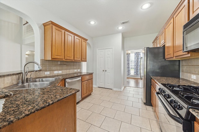 15127 Woodford Hollow Ln, Cypress, TX 77429 - kitchen with black appliances, arched walkways, a sink, tasteful backsplash, and recessed lighting
