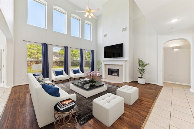 15127 Woodford Hollow Ln, Cypress, TX 77429 - living room featuring arched walkways, a towering ceiling, a ceiling fan, plenty of natural light, and a tiled fireplace