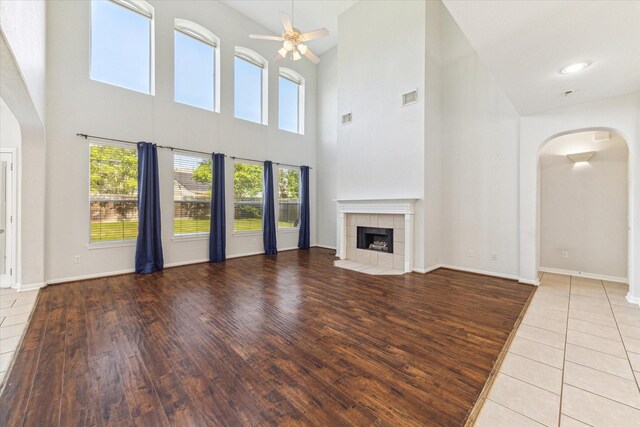 15127 Woodford Hollow Ln, Cypress, TX 77429 - unfurnished living room with arched walkways, ceiling fan, a towering ceiling, healthy amount of natural light, and wood finished floors