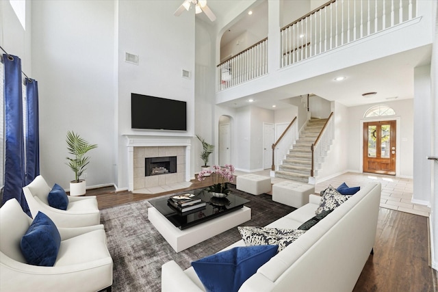 15127 Woodford Hollow Ln, Cypress, TX 77429 - living area with wood finished floors, a towering ceiling, stairway, baseboards, and a tiled fireplace
