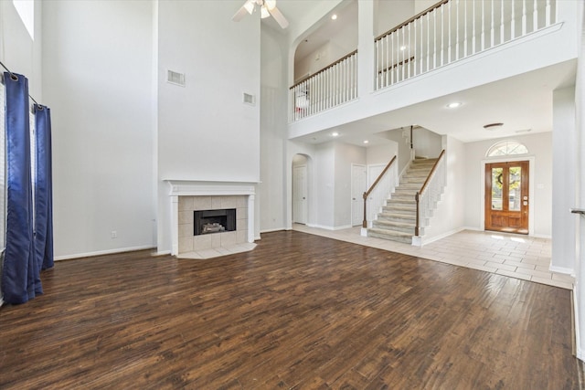 15127 Woodford Hollow Ln, Cypress, TX 77429 - unfurnished living room featuring wood finished floors, a towering ceiling, ceiling fan, baseboards, and a tile fireplace