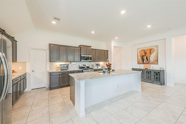 13510 Dovetail Canyon Ct, Rosharon, TX 77583 - kitchen with stainless steel appliances, backsplash, a center island with sink, light tile patterned flooring, and light stone counters