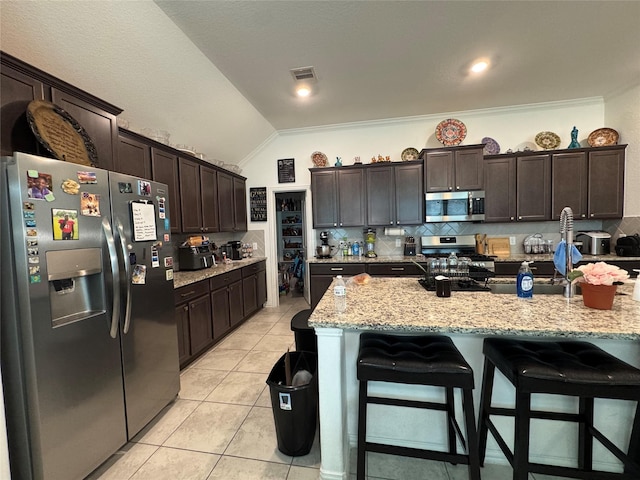13510 Dovetail Canyon Ct, Rosharon, TX 77583 - kitchen featuring stainless steel appliances, vaulted ceiling, a kitchen bar, decorative backsplash, and light tile patterned flooring