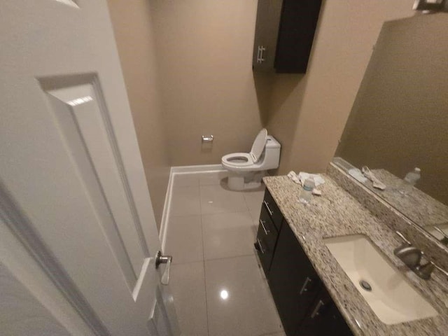 bathroom with vanity, toilet, tile patterned flooring, and baseboards