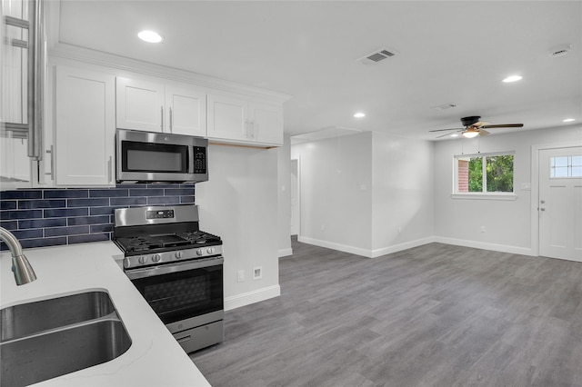 110 Prune St, La Marque, TX 77568 - kitchen with stainless steel appliances, a sink, white cabinets, baseboards, and a ceiling fan