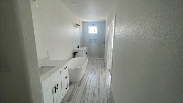 9316 Waller St, Houston, TX 77012 - full bathroom with vanity, a soaking tub, a textured wall, tile patterned flooring, and baseboards