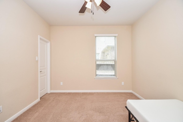 spare room with ceiling fan, light carpet, and baseboards