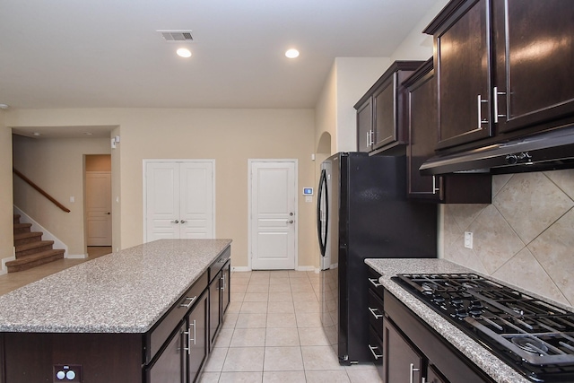 kitchen with black gas stovetop, under cabinet range hood, decorative backsplash, a center island, and dark brown cabinets