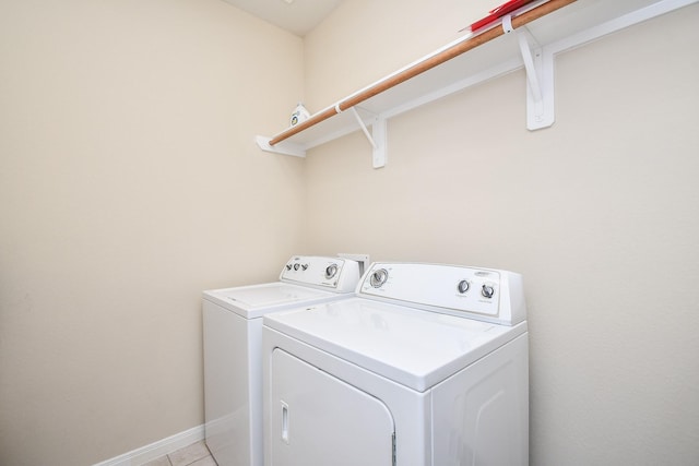 washroom featuring washing machine and dryer, baseboards, and light tile patterned floors