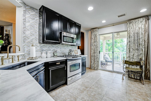 13600 Breton Ridge St Unit 25B, Houston, TX 77070 - kitchen featuring appliances with stainless steel finishes, a sink, dark cabinets, tasteful backsplash, and recessed lighting