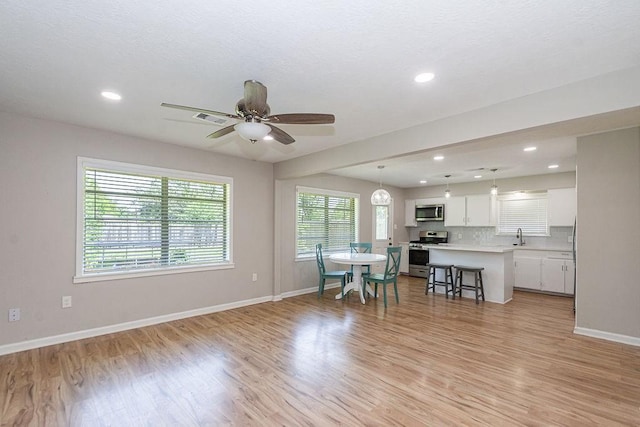 dining area featuring baseboards, light wood finished floors, a ceiling fan, and recessed lighting